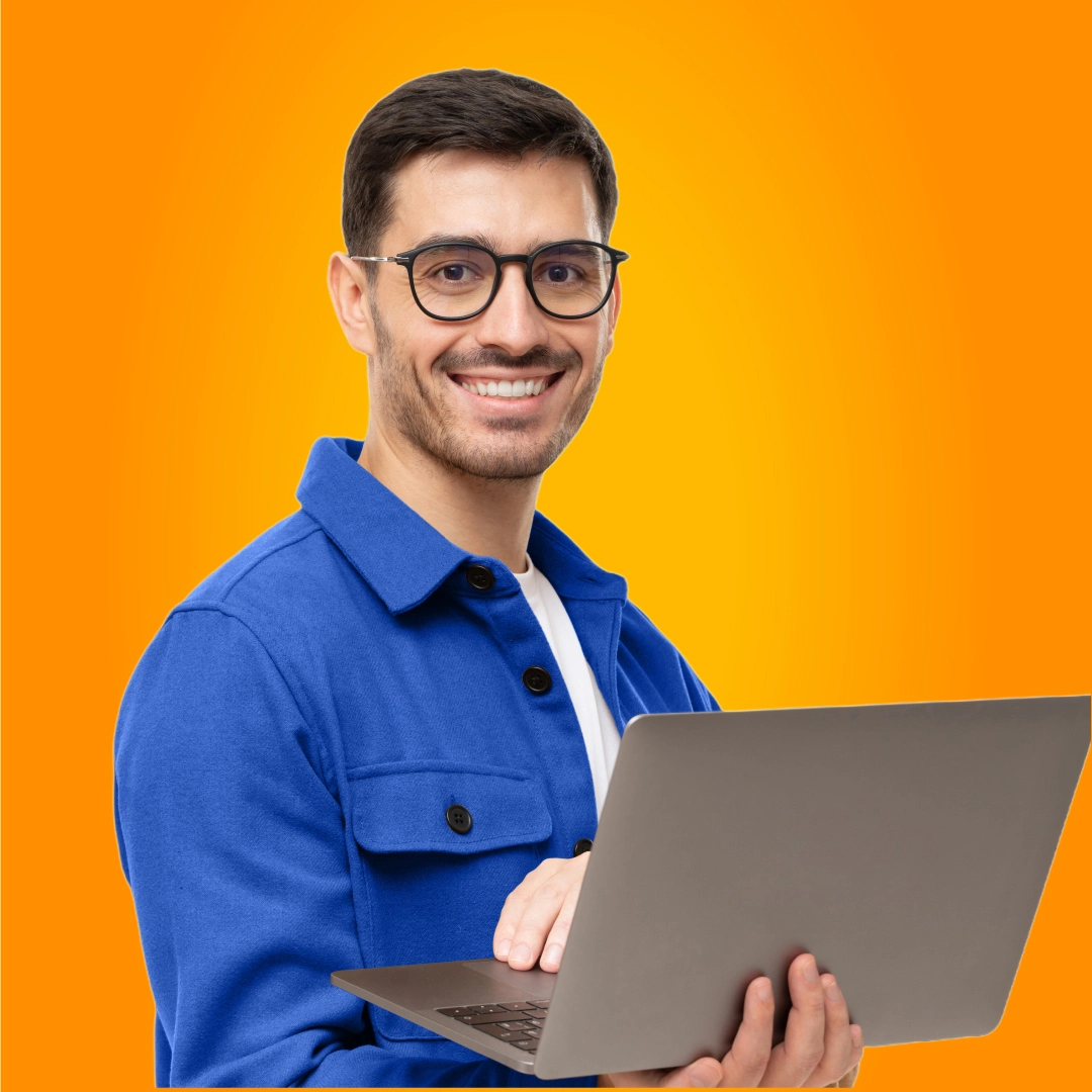 Smiling man wearing glasses and a blue jacket, holding a laptop against an orange background.